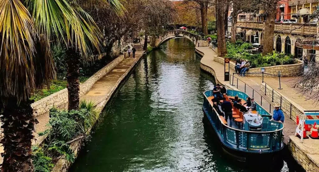 A serene evening along the San Antonio Riverwalk, where vibrant lights reflect off the water and historic architecture meets lively culture.